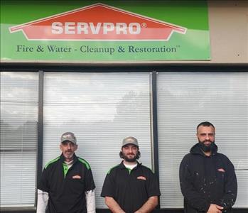 Our Reconstruction Team posing for a picture below a green SERVPRO sign