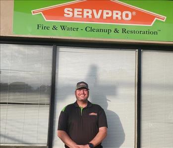 Our production manager Derek underneath a green SERVPRO sign