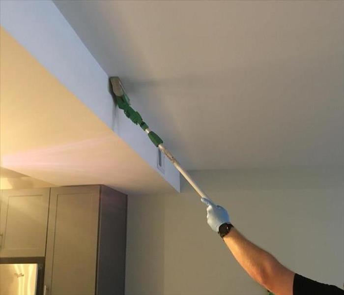 Man cleaning soot off of a ceiling with a rubber sponge
